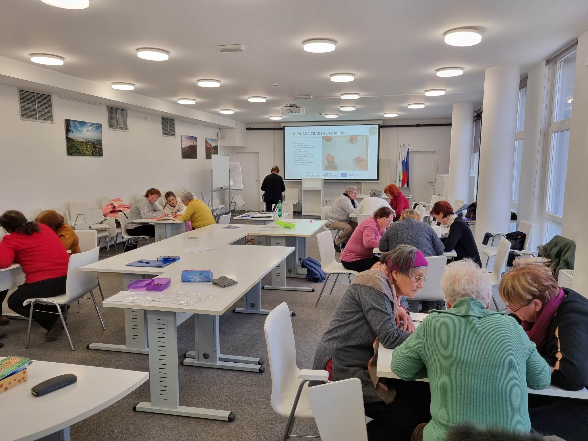 Udeleženci uživajo in se sproščajo ob barvanju fraktalov.